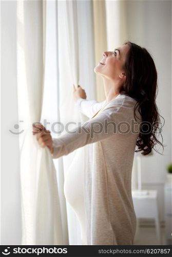 pregnancy, motherhood, people and expectation concept - happy pregnant woman opening window curtains at home