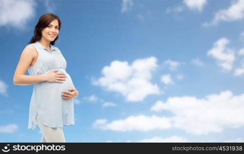 pregnancy, motherhood, people and expectation concept - happy pregnant woman touching her big belly over blue sky and clouds background