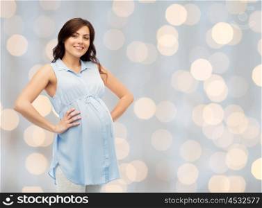 pregnancy, motherhood, people and expectation concept - happy pregnant woman touching her big belly over holidays lights background