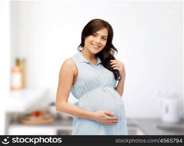 pregnancy, motherhood, people and expectation concept - happy pregnant woman touching her big belly over home kitchen room background