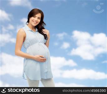 pregnancy, motherhood, people and expectation concept - happy pregnant woman touching her big belly over blue sky and clouds background