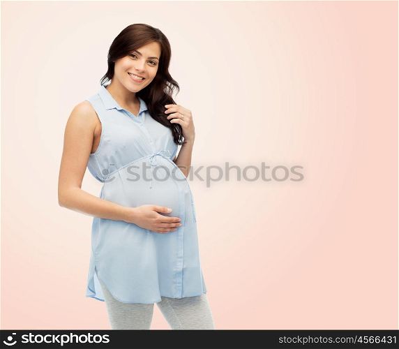 pregnancy, motherhood, people and expectation concept - happy pregnant woman touching her big belly over beige background