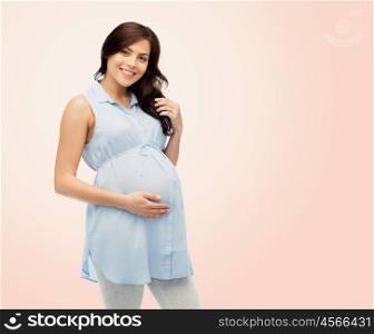 pregnancy, motherhood, people and expectation concept - happy pregnant woman touching her big belly over beige background