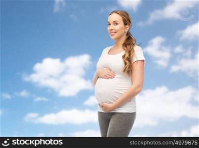 pregnancy, motherhood, people and expectation concept - happy pregnant woman touching her big belly over blue sky and clouds background. happy pregnant woman touching her belly over sky