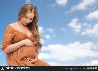 pregnancy, motherhood, people and expectation concept - happy pregnant woman touching her big belly over blue sky and clouds background. happy pregnant woman touching her big belly