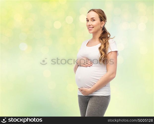 pregnancy, motherhood, people and expectation concept - happy pregnant woman touching her big belly over summer green lights background. happy pregnant woman touching her big belly