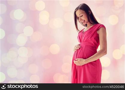 pregnancy, motherhood, people and expectation concept - happy pregnant woman with big tummy over pink holidays lights background