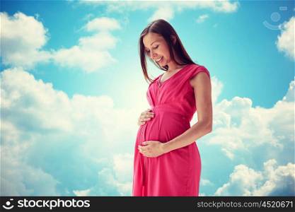 pregnancy, motherhood, people and expectation concept - happy pregnant woman with big tummy over blue sky and clouds background