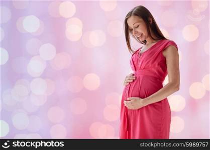 pregnancy, motherhood, people and expectation concept - happy pregnant woman with big tummy over pink holidays lights background