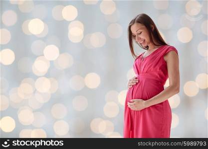 pregnancy, motherhood, people and expectation concept - happy pregnant woman with big tummy over holidays lights background