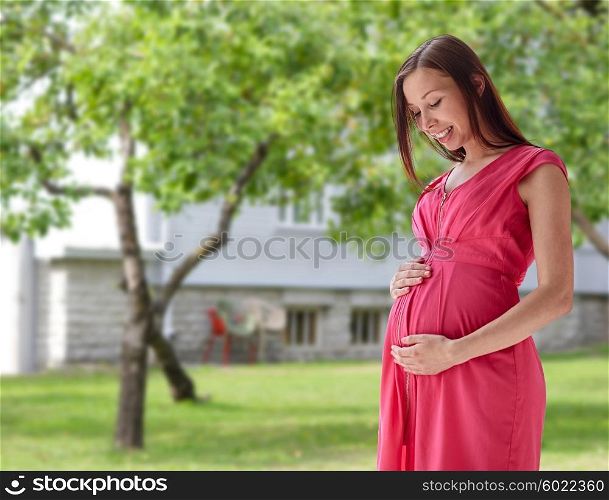 pregnancy, motherhood, people and expectation concept - happy pregnant woman with big tummy over home yard or garden background