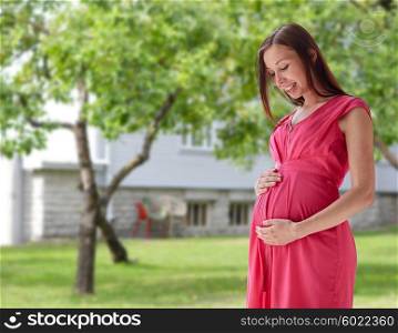 pregnancy, motherhood, people and expectation concept - happy pregnant woman with big tummy over home yard or garden background