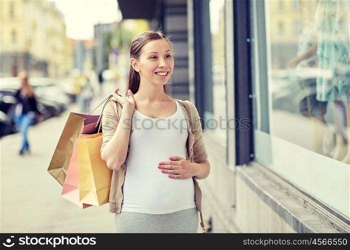 pregnancy, motherhood, people and expectation concept - happy smiling pregnant woman with shopping bags at city street