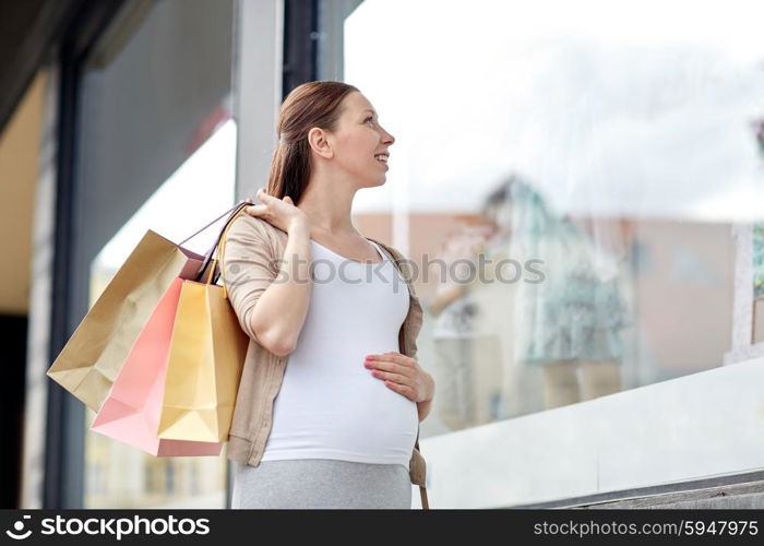 pregnancy, motherhood, people and expectation concept - happy smiling pregnant woman with shopping bags at city street