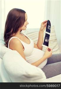 pregnancy, motherhood, people and medicine concept - happy pregnant woman looking at ultrasound image at home