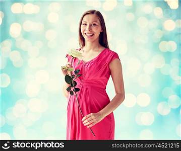 pregnancy, motherhood, people, holidays and expectation concept - happy pregnant woman with white rose flower over blue holidays lights background