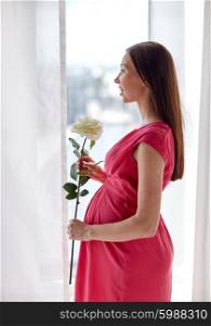 pregnancy, motherhood, people, holidays and expectation concept - happy pregnant woman with white rose flower at home