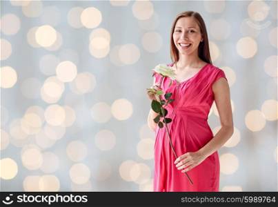 pregnancy, motherhood, people, holidays and expectation concept - happy pregnant woman with white rose flower over holidays lights background