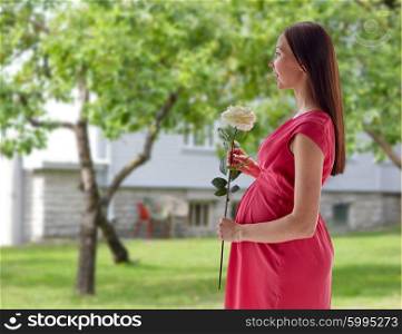 pregnancy, motherhood, people, holidays and expectation concept - happy pregnant woman with white rose flower over home yard or garden background