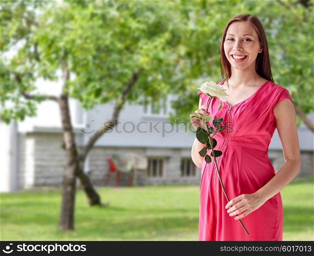 pregnancy, motherhood, people, holidays and expectation concept - happy pregnant woman with white rose flower over home yard or garden background