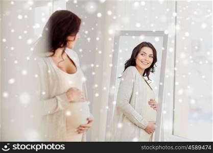 pregnancy, motherhood, people, winter and expectation concept - happy pregnant woman looking to mirror at home over snow