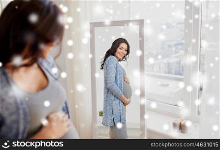 pregnancy, motherhood, people, winter and expectation concept - happy pregnant woman looking to mirror at home over snow
