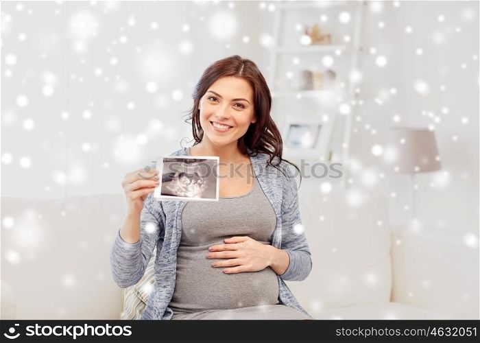 pregnancy, motherhood, people, winter and medicine concept - happy pregnant woman holding at ultrasound image at home over snow