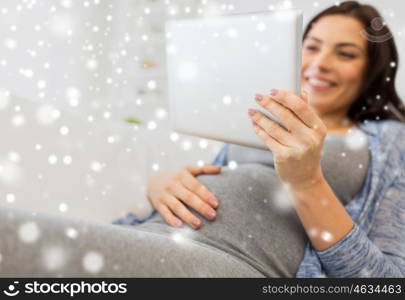 pregnancy, motherhood, technology, people and expectation concept - close up of happy pregnant woman with tablet pc computer at home over snow