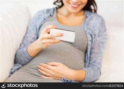 pregnancy, motherhood, technology, people and expectation concept - close up of happy pregnant woman with smartphone at home
