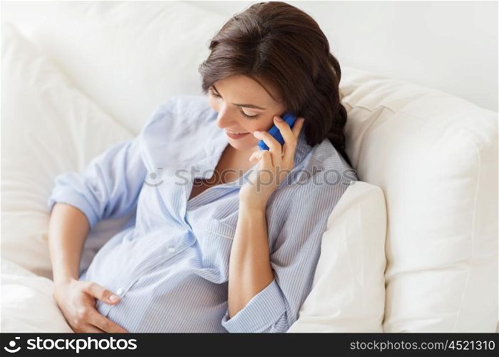 pregnancy, motherhood, technology, people and expectation concept - happy pregnant woman calling on smartphone in bed at home
