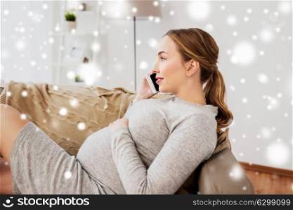pregnancy, motherhood, technology, people and expectation concept - happy pregnant woman calling on smartphone at home over snow. happy pregnant woman calling on smartphone at home