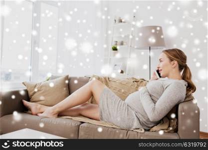 pregnancy, motherhood, technology, people and expectation concept - happy pregnant woman calling on smartphone at home over snow. happy pregnant woman calling on smartphone at home