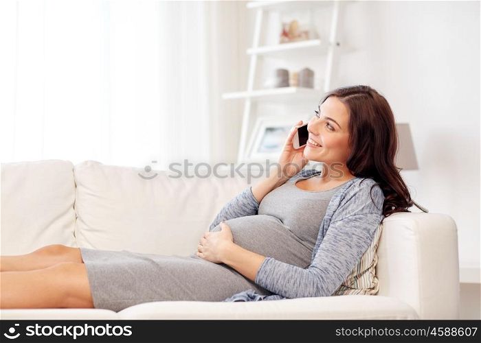 pregnancy, motherhood, technology, people and expectation concept - happy pregnant woman calling on smartphone at home