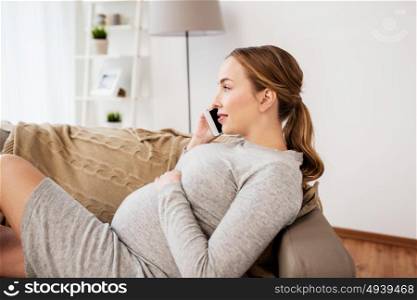 pregnancy, motherhood, technology, people and expectation concept - happy pregnant woman calling on smartphone at home. happy pregnant woman calling on smartphone at home