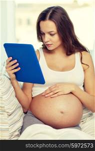 pregnancy, motherhood, technology, people and expectation concept - happy pregnant woman with tablet pc computer at home
