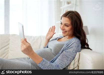 pregnancy, motherhood, technology, people and expectation concept - happy pregnant woman with tablet pc computer having video call and waving hand at home