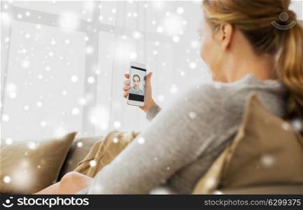 pregnancy, motherhood, technology, people and expectation concept - happy pregnant woman with smartphone taking selfie at home over snow. pregnant woman taking smartphone selfie at home