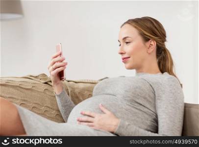 pregnancy, motherhood, technology, people and expectation concept - happy pregnant woman with smartphone at home. happy pregnant woman with smartphone at home