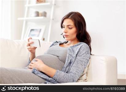 pregnancy, motherhood, technology, people and expectation concept - sad pregnant woman with smartphone at home