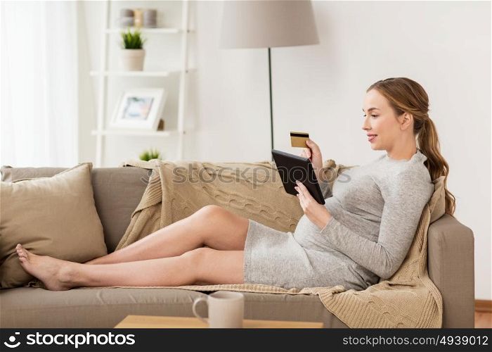pregnancy, online shopping, technology and people concept - happy pregnant woman with tablet pc computer and credit card at home. pregnant woman with tablet pc and credit card
