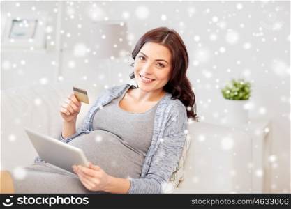 pregnancy, online shopping, technology, winter and people concept - happy pregnant woman with tablet pc computer and credit card at home over snow