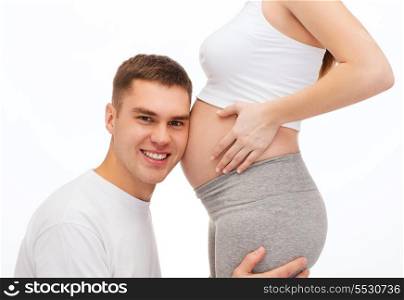 pregnancy, parenthood and happiness concept - happy father listening belly of his pregnant wife