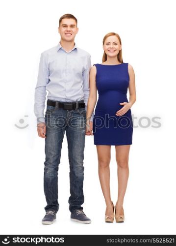 pregnancy, parenthood and happiness concept - happy young family expecting child holding hands