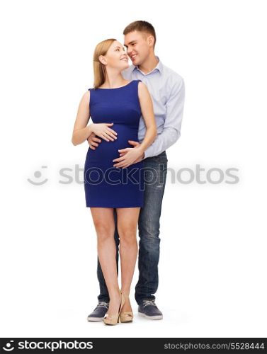 pregnancy, parenthood and happiness concept - happy young family expecting child looking at each other
