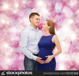 pregnancy, parenthood and happiness concept - happy young family expecting child looking at each other