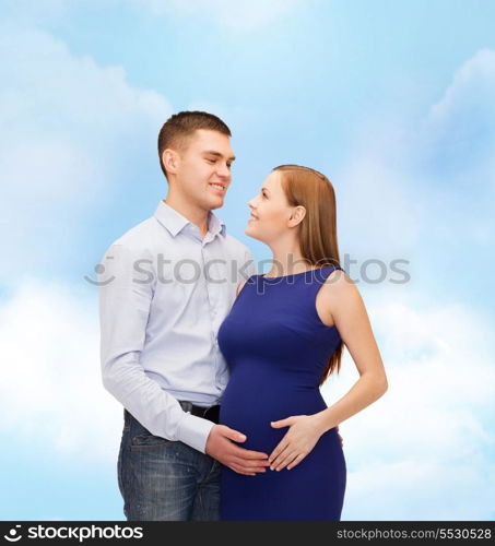 pregnancy, parenthood and happiness concept - happy young family expecting child looking at each other