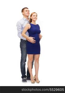 pregnancy, parenthood and happiness concept - happy young family expecting child looking up