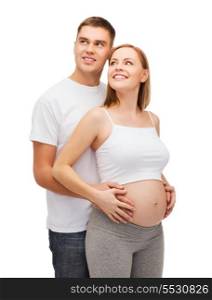 pregnancy, parenthood and happiness concept - happy young family expecting child looking up