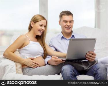 pregnancy, parenthood, internet and technology concept - expecting family with laptop computer