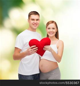 pregnancy, parenthood, love and happiness concept - happy young family expecting child with big red heart